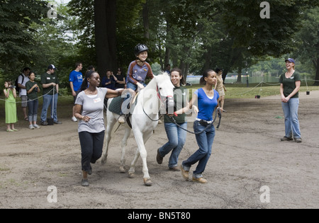 Les enfants handicapés reçoivent un apprentissage de thérapie développementale pour monter à cheval, connu sous le nom d'hippothérapie. Banque D'Images