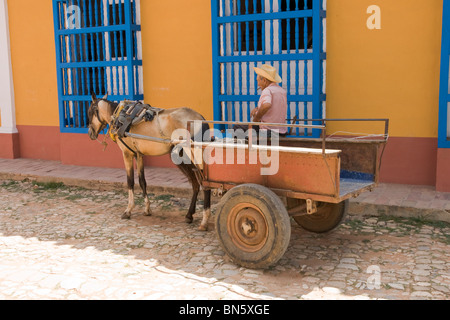 Ancien ouvrier assis à l'ombre sur son chariot dans une rue à Cuba. Banque D'Images