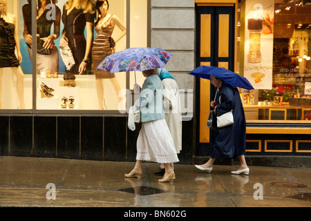 Trois femmes avec des parasols sur un jour de pluie. La rue Saint-Jean, Québec, Canada. Banque D'Images