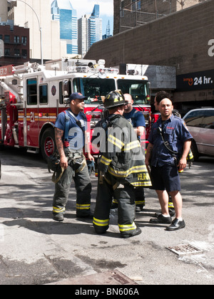 Petit groupe de pompiers de New York près de leur cluster chariot sur une petite rue de Manhattan se détendre après le feu est éteint Banque D'Images