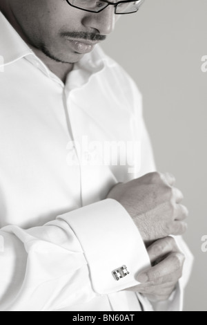 Man putting on cufflinks Banque D'Images