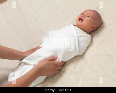 L'emmaillotement mère pleurer un bébé garçon de six semaines