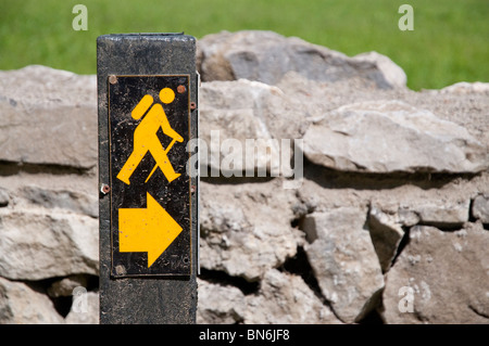 Walking route signer en Irlande, en face d'un mur en pierre sèche. Banque D'Images