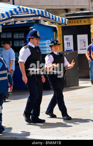 Londres Gay Pride , policier avec policewoman en uniforme en patrouille à pied & chatting Banque D'Images