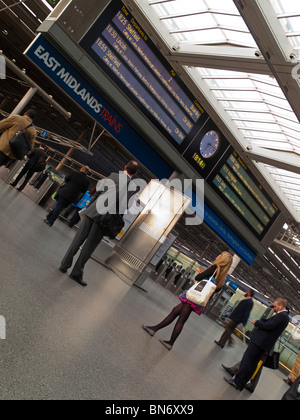 Les passagers qui attendent pour les trains à l'East Midlands à St Pancras à Londres l'article par le signal d'information et les obstacles Banque D'Images