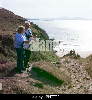 Un vieux couple randonnées avec les bâtons de marche et randonnée en regardant une carte sur le chemin côtier du Pembrokeshire, Pays de Galles Grande-bretagne UK KATHY DEWITT Banque D'Images