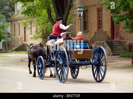 Les touristes profiter d'une balade en calèche à travers les rues de la ville coloniale de Williamsburg, au xviiie siècle un salon-attraction historique en Virginie, aux États-Unis. Banque D'Images