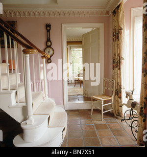 Chaise ancienne à côté d'ouvrir la porte de salle à manger en pays rose hall avec moquette crème sur escalier peint en blanc Banque D'Images