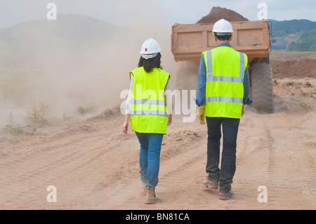 Les travailleurs de la construction à marcher derrière dump truck Banque D'Images