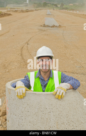 Hispanic construction worker standing in tuyau ciment Banque D'Images