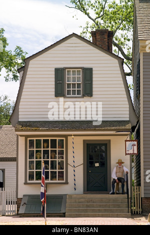 Un marchand en costume d'attend à l'extérieur pour les visiteurs de sa boutique de perruquier sur Duc de Gloucester Street dans le quartier historique de la ville coloniale de Williamsburg en Virginie, aux États-Unis. Banque D'Images