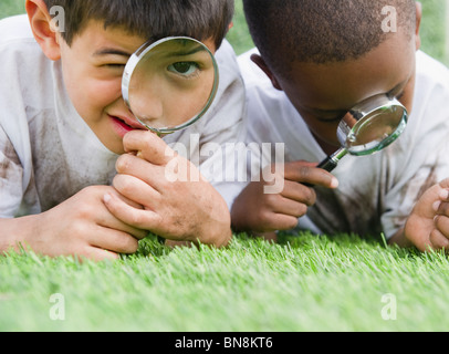 Les garçons à l'herbe à l'intermédiaire de loupes Banque D'Images