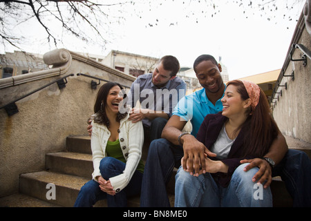 Rire des couples sitting on steps ensemble Banque D'Images