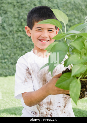 Mixed Race boy holding plante jardin Banque D'Images