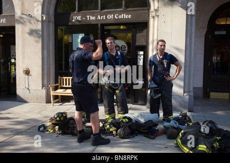 Passant et les premiers intervenants sur les lieux d'un trou de feu sur West 23rd Street dans le quartier de Chelsea à la mode de New York Banque D'Images