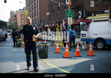 Passant et les premiers intervenants sur les lieux d'un trou de feu sur West 23rd Street dans le quartier de Chelsea à la mode de New York Banque D'Images