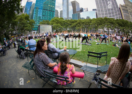 Des centaines de pratiquants de yoga de tous les niveaux participent à une classe de yoga donnés dans Bryant Park à New York Banque D'Images