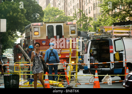 Passant et les premiers intervenants sur les lieux d'un trou de feu sur West 23rd Street dans le quartier de Chelsea à la mode de New York Banque D'Images