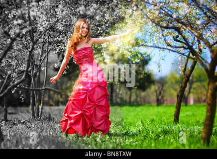 Jeune fée femme en robe rouge peinture jardin. Banque D'Images