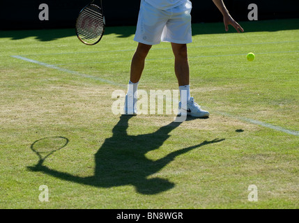 Ombre d'un joueur de rebondir la balle avant de servir au cours de la Tennis de Wimbledon 2010 Banque D'Images