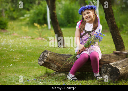 Petite fille avec un chapelet fait de fleurs bleues Banque D'Images