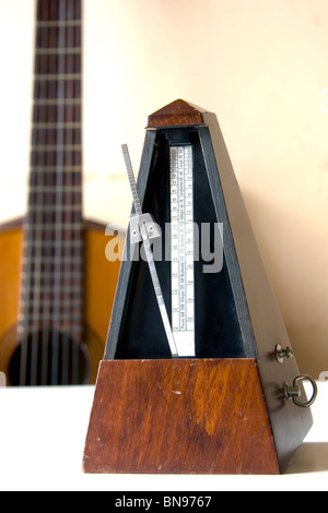 Ancien métronome sur table blanc avec guitare derrière (photo verticale) Banque D'Images