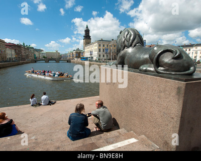 Les gens assis à côté de lion de bronze au bord de l'eau par canal garde dans le centre de Göteborg Suède Banque D'Images