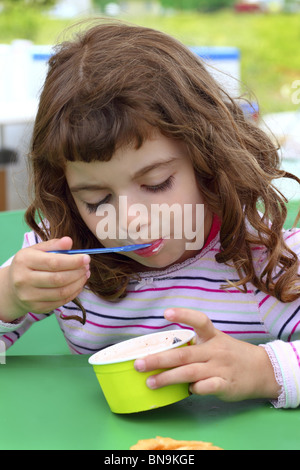 Brunette little girl eating ice cream d'été cuillère couleur Banque D'Images