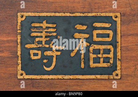 Old metal sign sur bois avec des caractères chinois que la longévité moyenne, bonheur et longue vie. Banque D'Images