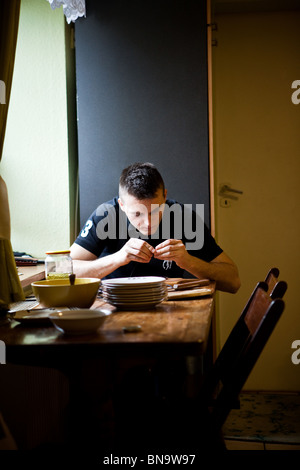 Jeune homme assis dans une cuisine et de cuisine Banque D'Images