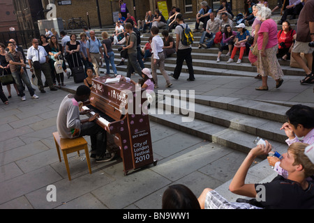 Les foules sont divertis par le pianiste jouant dans le cadre de City of London's jouer un piano music festival. Banque D'Images