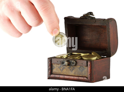 Ancien coffret plein de pièces de monnaie et une main tenant deux euros pièce Banque D'Images