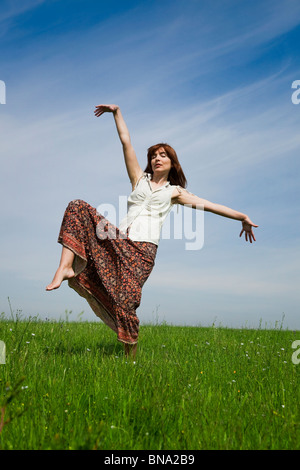 Jeune femme faisant danser pose sur une verte prairie Banque D'Images