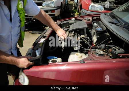 L'homme dépose d'un démarreur de voiture à breakers cour. Banque D'Images