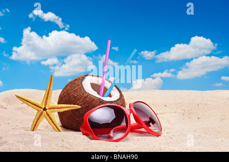 Une noix de coco, étoiles et un lunettes de soleil sur une plage Banque D'Images