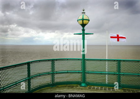 Lampadaire et St George's drapeau à la brise d'un ciel nuageux Estuaire du Severn sur l'extrémité de la jetée de Clevedon dans Somerset Banque D'Images