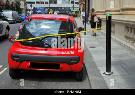 Le câble de charge électrique relie la voiture rouge Citroën au point de jus de bollard d'appoint électrique par Westminster City Council Climate change concerne Londres Royaume-Uni Banque D'Images