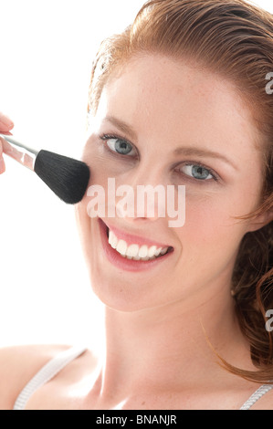 Jeune femme s'applique sur les joues blush Banque D'Images