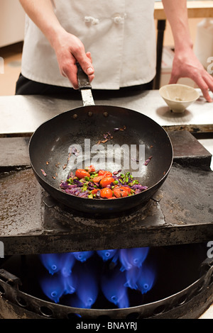 Male chef poêle Wok avec en cuisine commerciale Banque D'Images