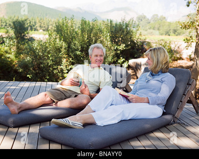 D'âge mûr se détendre sur des chaises longues avec des livres Banque D'Images