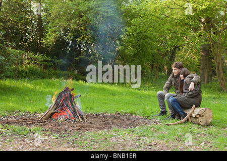 Jeune couple par feu de camp Banque D'Images
