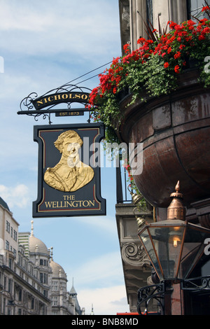 Le Wellington, enseigne de pub, grand bol de géraniums et lampe à gaz dans le Strand, London. Banque D'Images