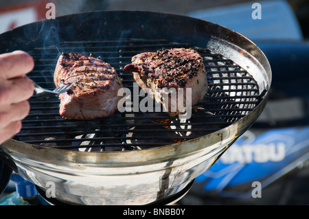 Deux Biftecks de filet mignon sont grillées sur un barbecue extérieur ronde à l'arrière d'un bateau. Banque D'Images