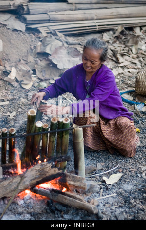 Vieille Femme en utilisant le bambou dans la cuisine sur un feu ouvert à Mae Sam Laep, un camp de réfugiés birmans, province de Mae Hong Son, Thaïlande Banque D'Images