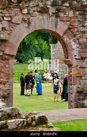 Abbaye de Dryburgh dans la région des Scottish Borders. Une fête de mariage sur la pelouse par une porte voûtée. Banque D'Images