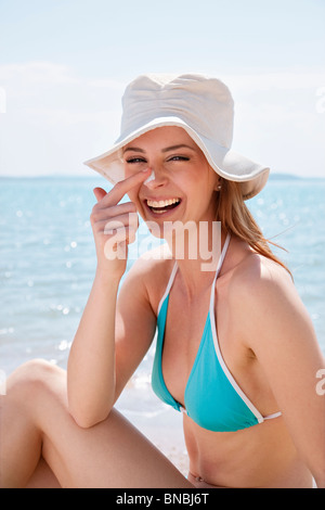 Woman putting on crème solaire à la plage Banque D'Images