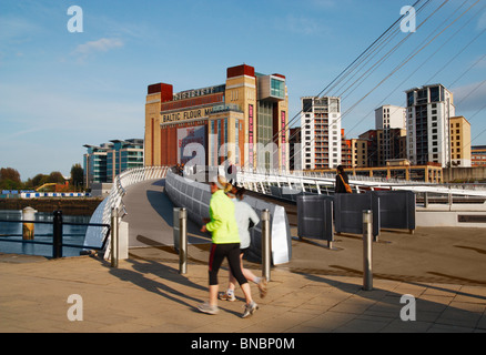 Deux femmes près de jogging le Millennium Bridge sur Newcastle Quayside. Baltic Centre for contemporary arts à l'arrière-plan Banque D'Images