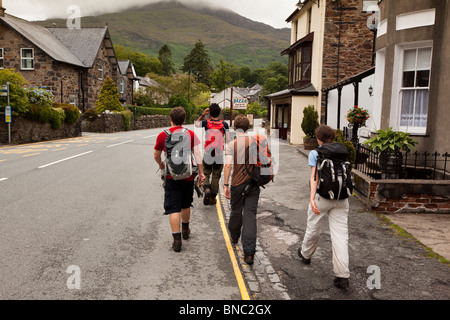 Royaume-uni, Pays de Galles, de Beddgelert, Snowdonia, quatre jeunes personnes marchant dans la route à travers le village Banque D'Images