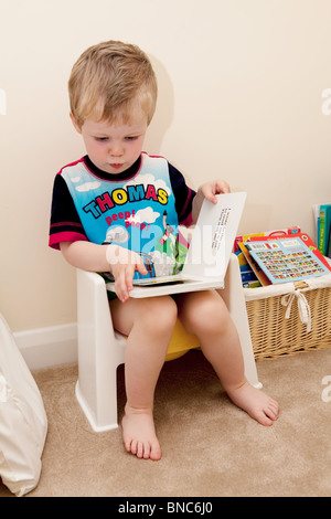 Jeune garçon à la lecture sur son pot. Banque D'Images