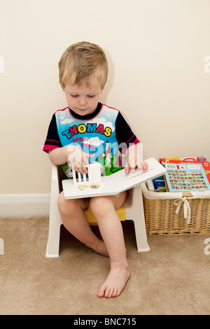 Jeune garçon à la lecture sur son pot. Banque D'Images